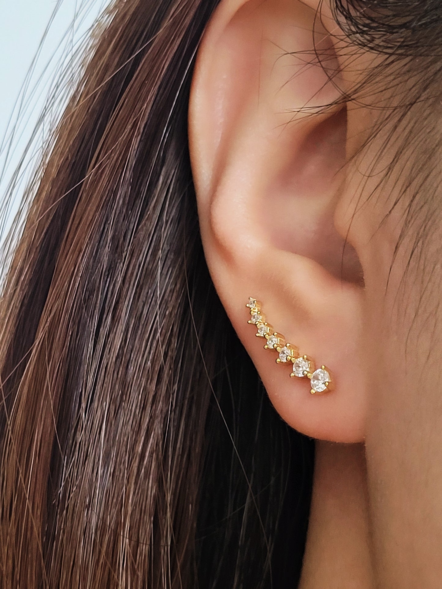 Close-up of a woman's ear wearing an 18K gold-plated cubic zirconia climber earring, highlighting the elegant and minimalist design.