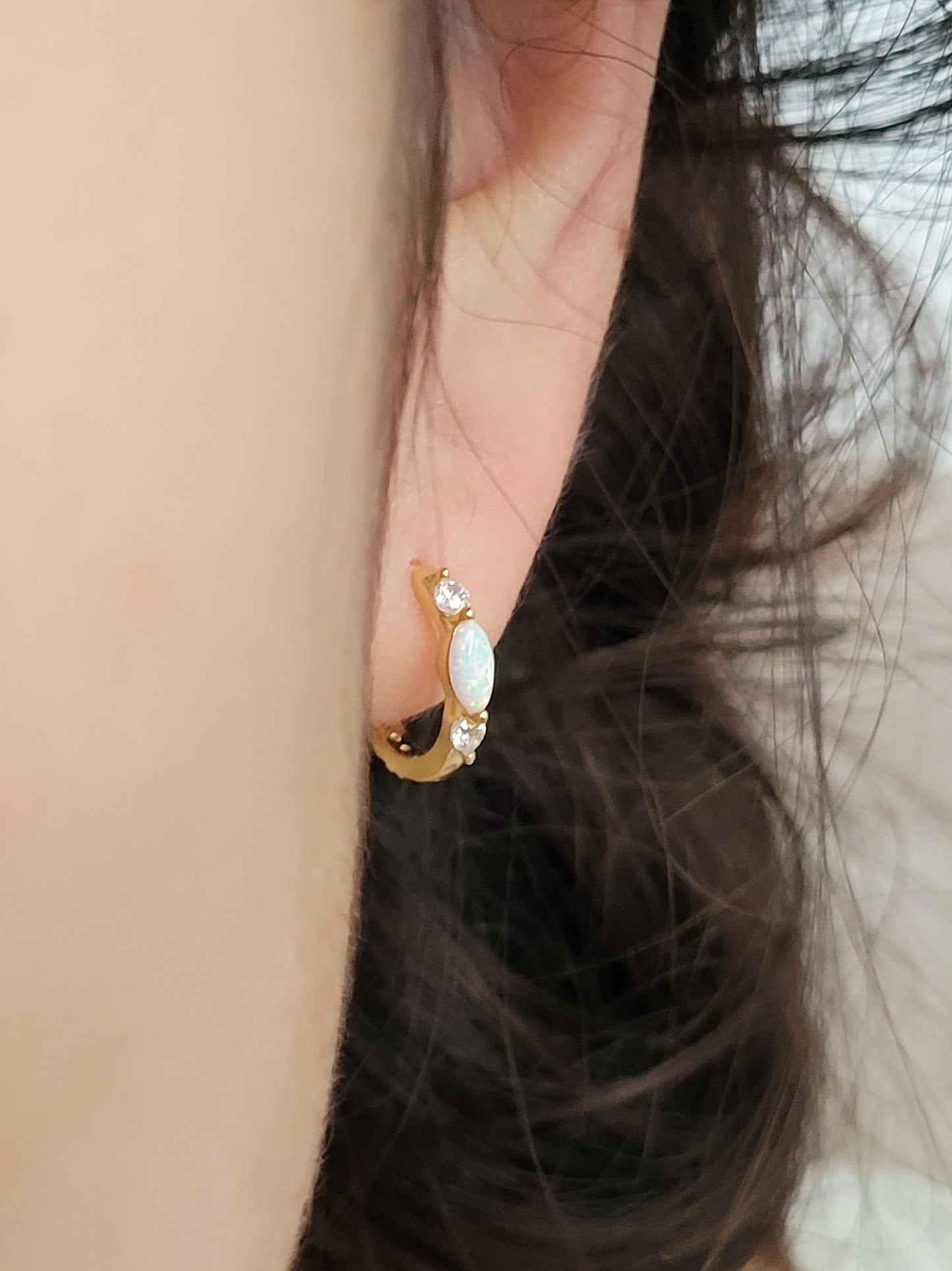 Close up of 18k gold plated sterling silver marquise opal huggie earrings, featuring a luminous opal accented with sparkling cubic zirconia.