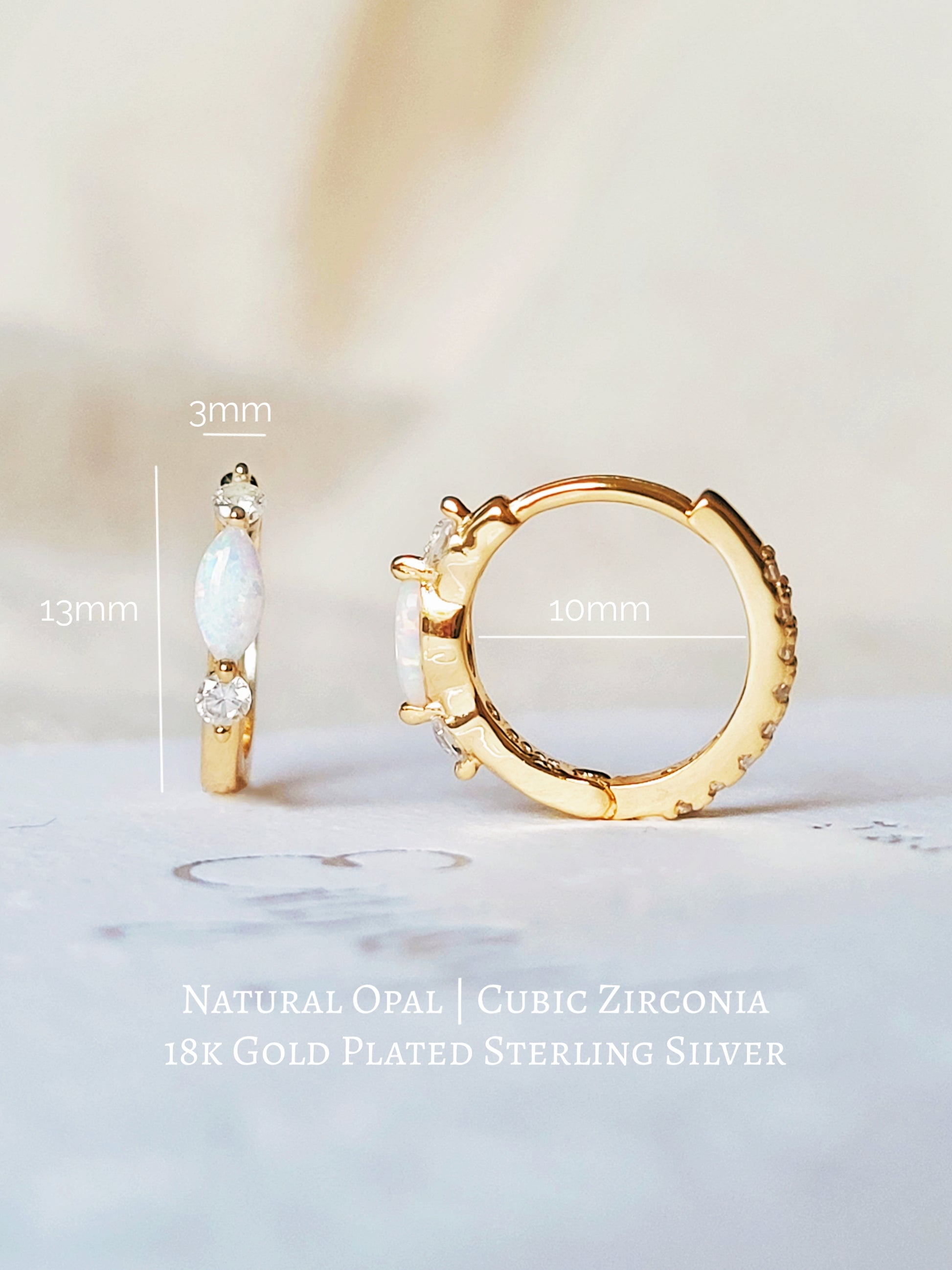 Close up of 18k gold plated sterling silver marquise opal huggie earrings, featuring a luminous opal accented with sparkling cubic zirconia.