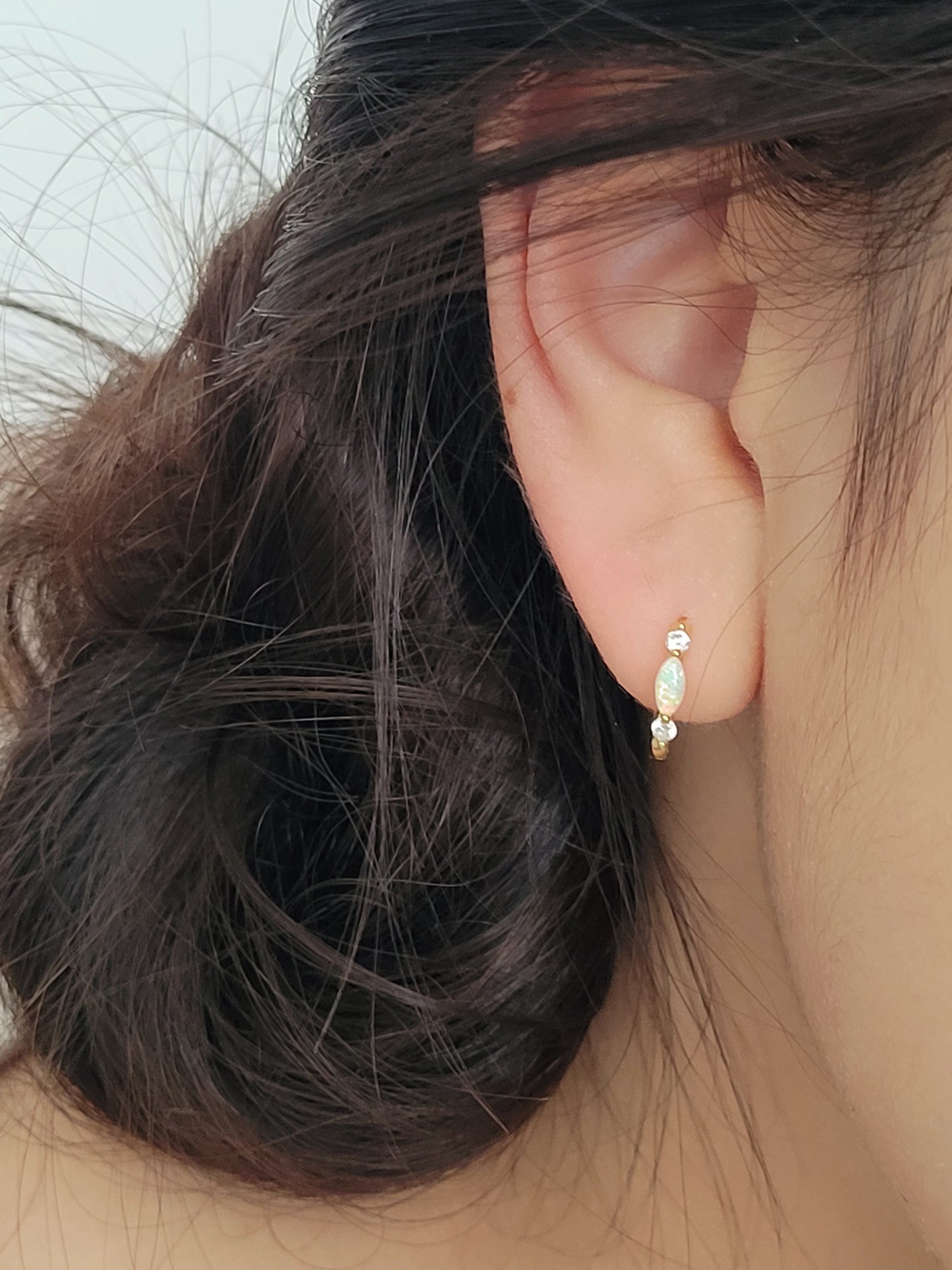 Close up of 18k gold plated sterling silver marquise opal huggie earrings, featuring a luminous opal accented with sparkling cubic zirconia.