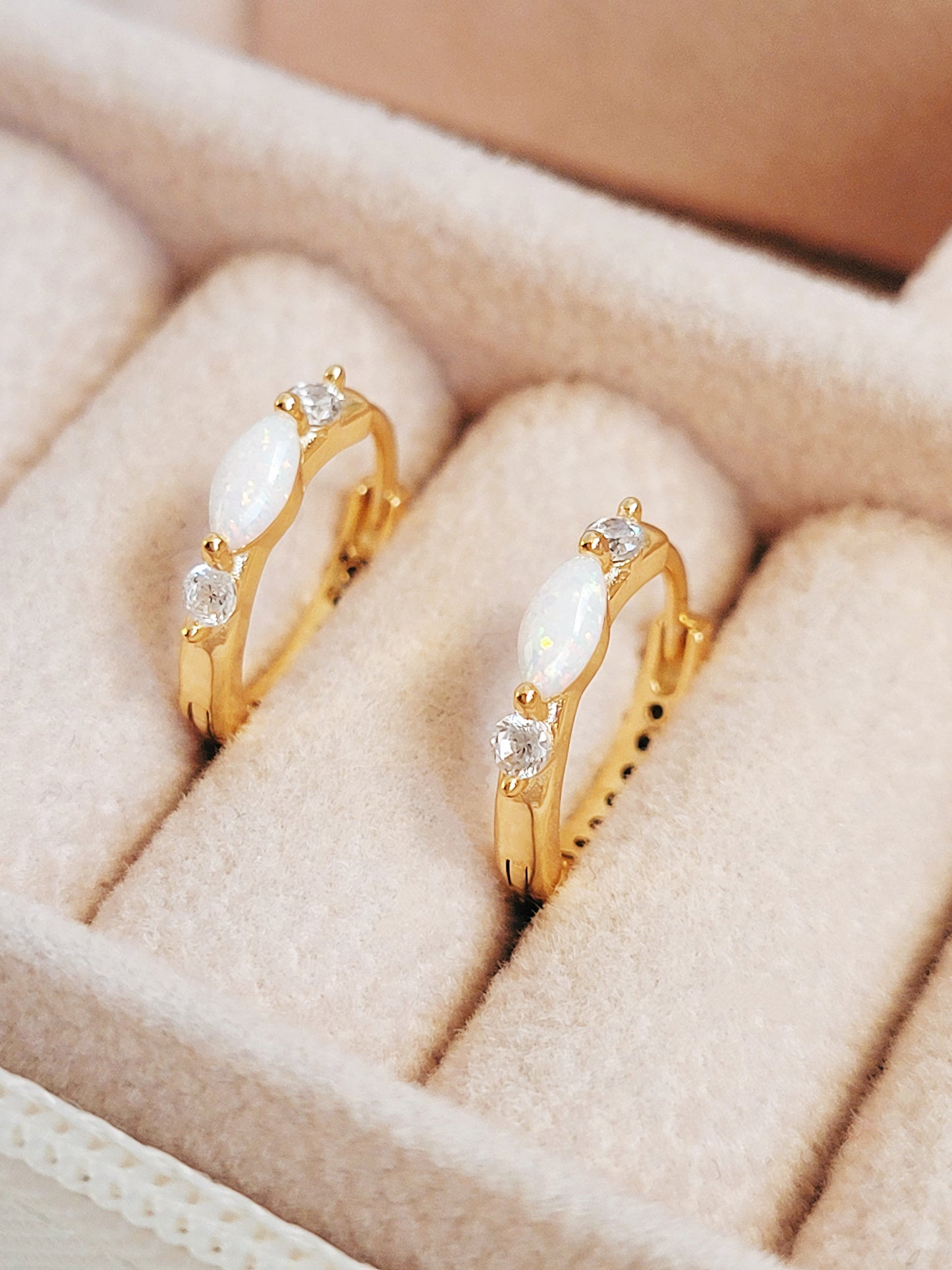 Close up of 18k gold plated sterling silver marquise opal huggie earrings, featuring a luminous opal accented with sparkling cubic zirconia.