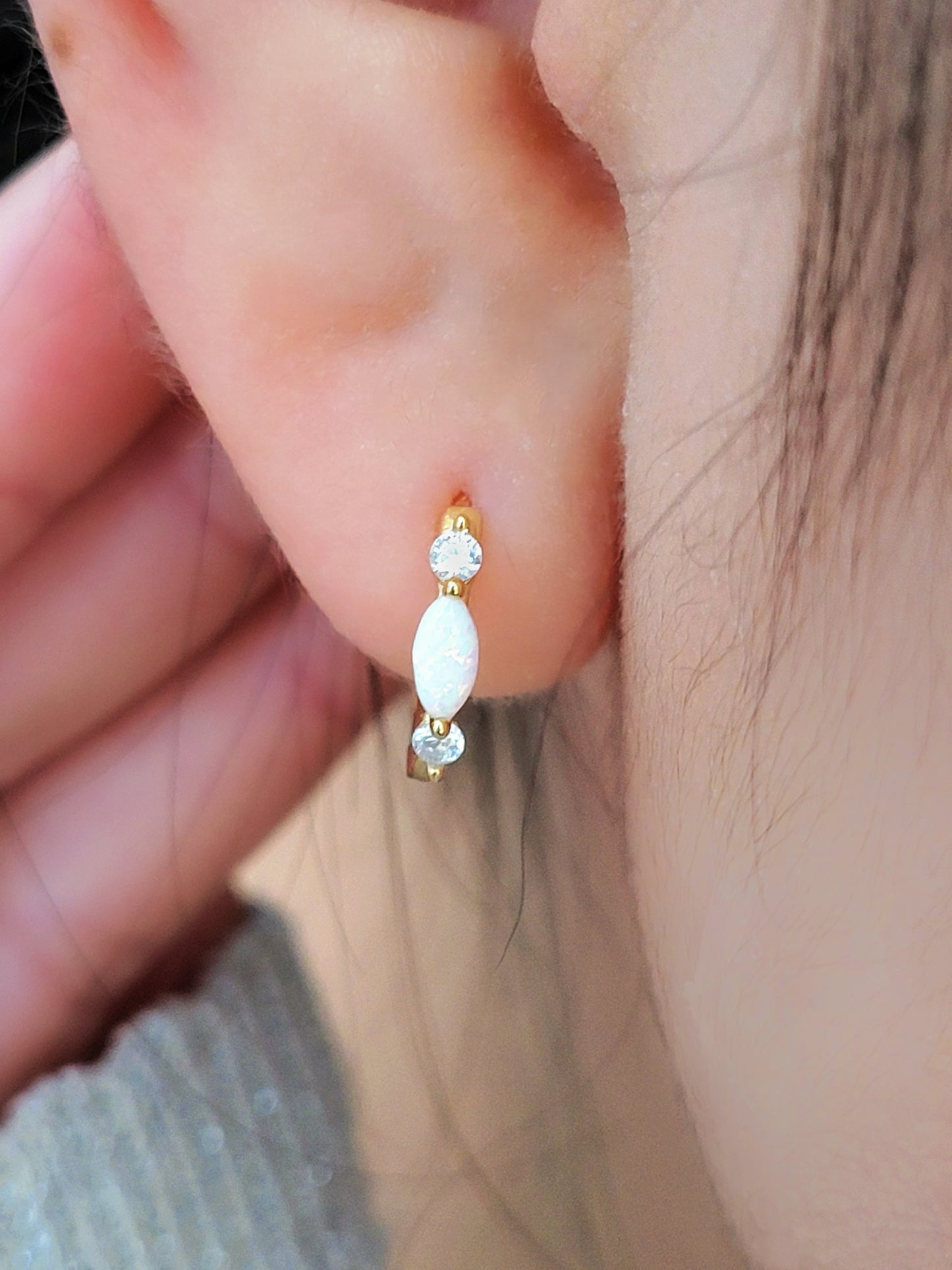 Close up of 18k gold plated sterling silver marquise opal huggie earrings, featuring a luminous opal accented with sparkling cubic zirconia.