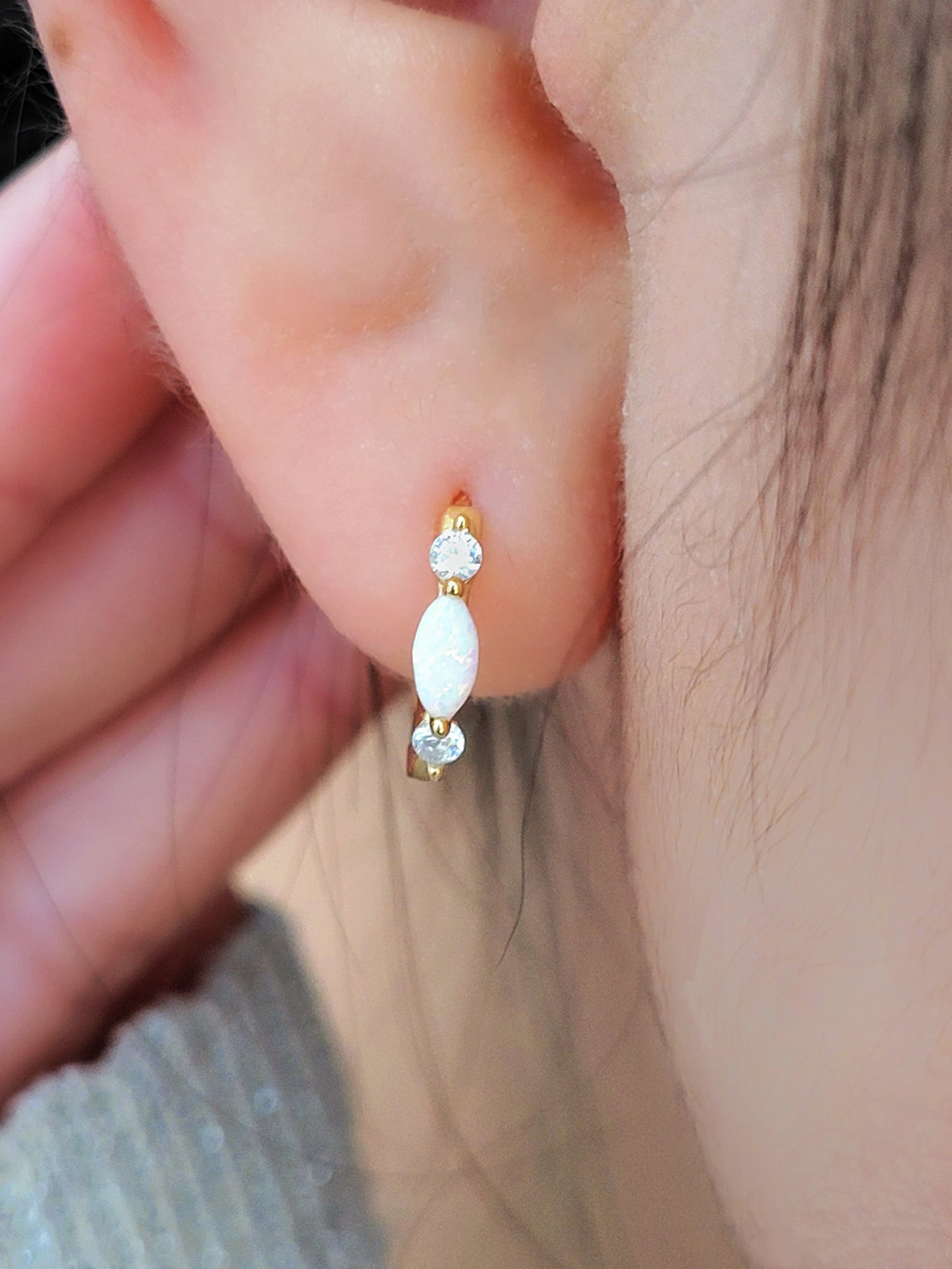 Close up of 18k gold plated sterling silver marquise opal huggie earrings, featuring a luminous opal accented with sparkling cubic zirconia.