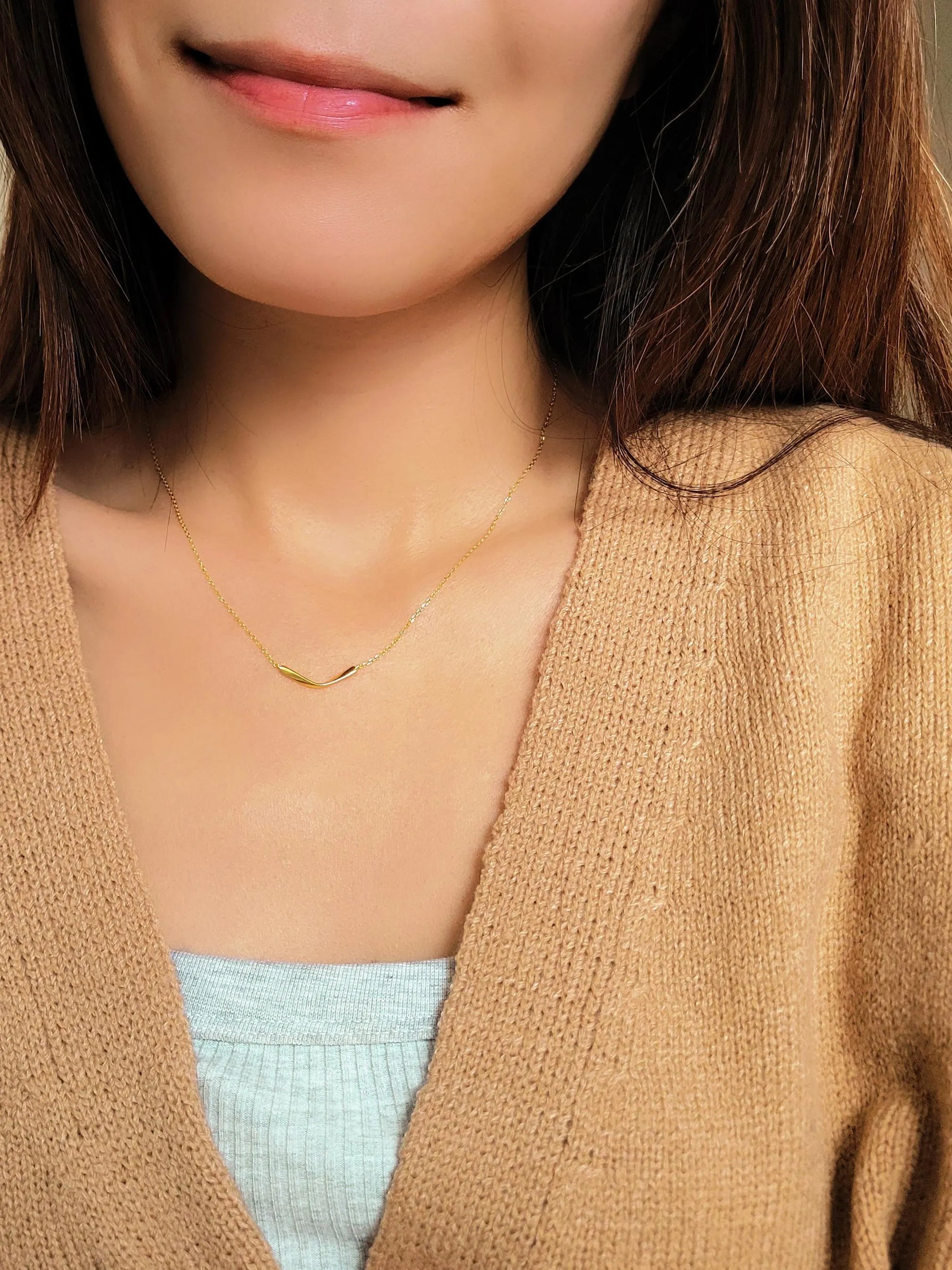 A girl wearing the simple gold bar necklace with beige cardigan, simple and minimalist outfit