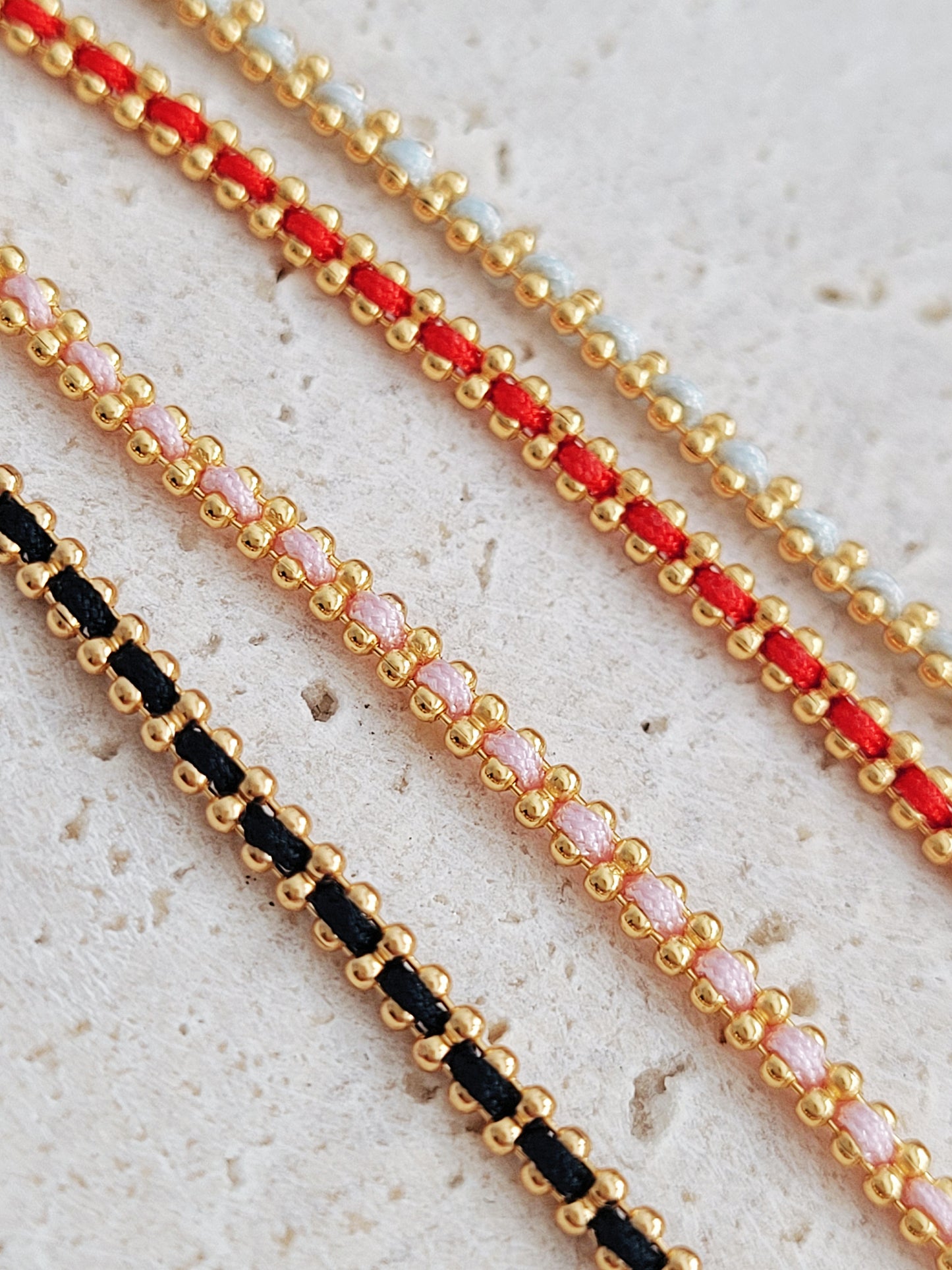 Gold-plated sterling silver string bracelets in Black, Blue, Red and Pink, perfect as friendship bracelets or meaningful graduation gifts for everyday wear.