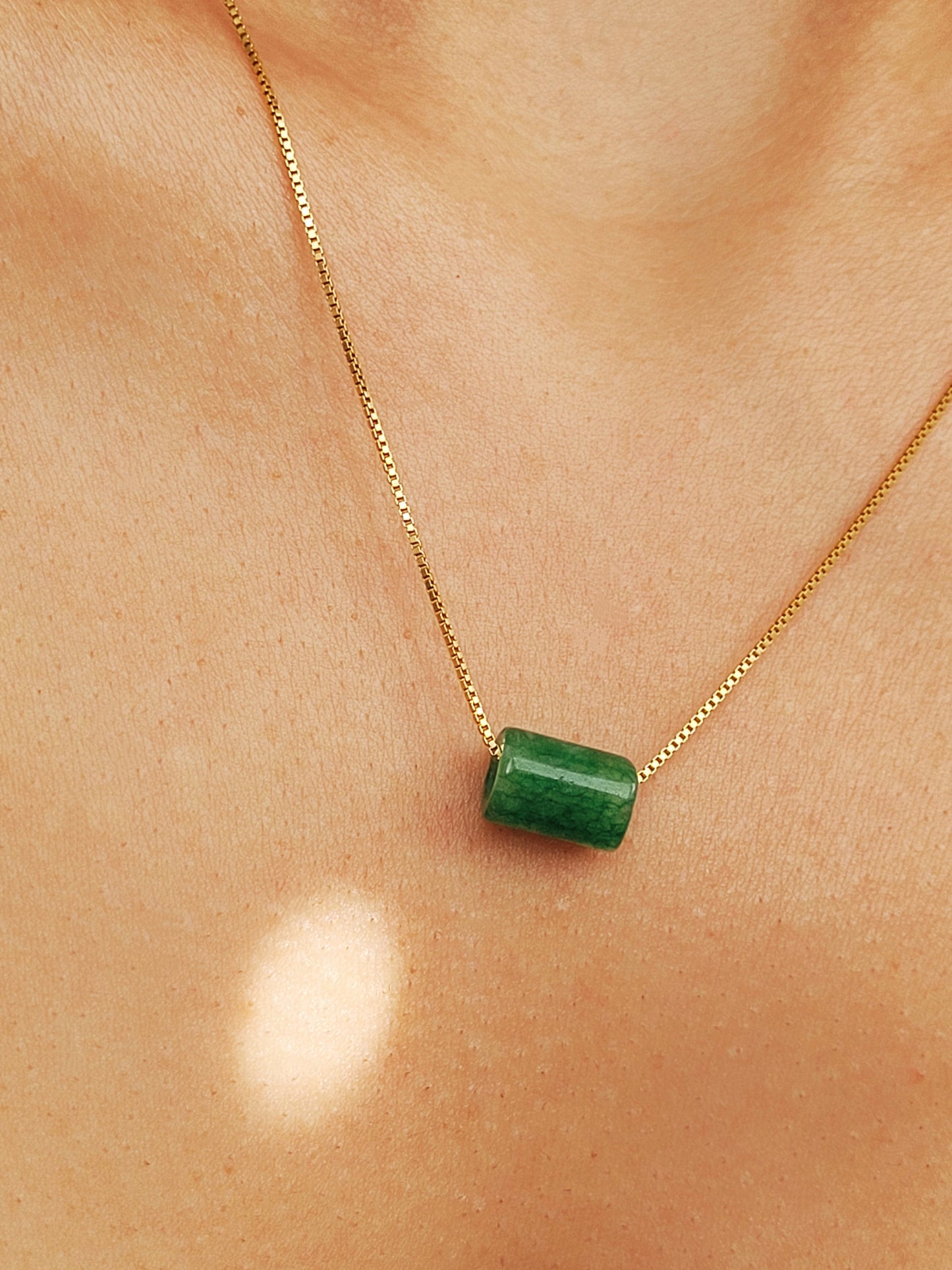 A natural green jade bead necklace with a polished finish, strung on a gold-plated sterling silver chain, offering a minimalist and elegant style.