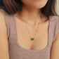 A natural green jade bead necklace with a polished finish, strung on a gold-plated sterling silver chain, offering a minimalist and elegant style.