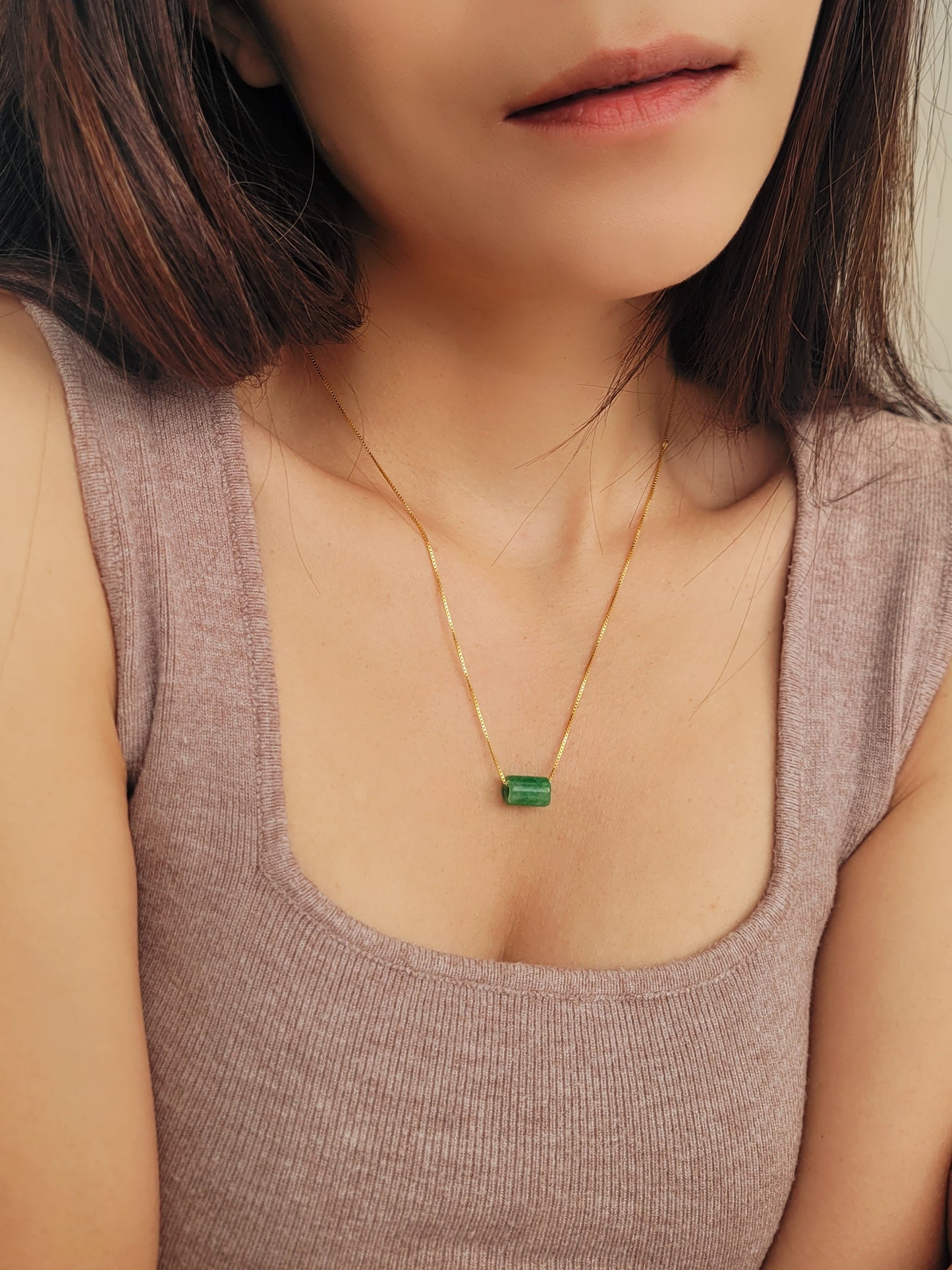 A natural green jade bead necklace with a polished finish, strung on a gold-plated sterling silver chain, offering a minimalist and elegant style.