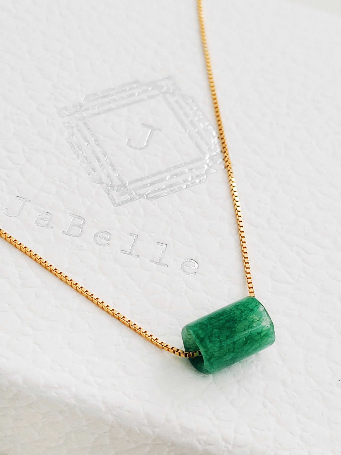 A natural green jade bead necklace with a polished finish, strung on a gold-plated sterling silver chain, offering a minimalist and elegant style.