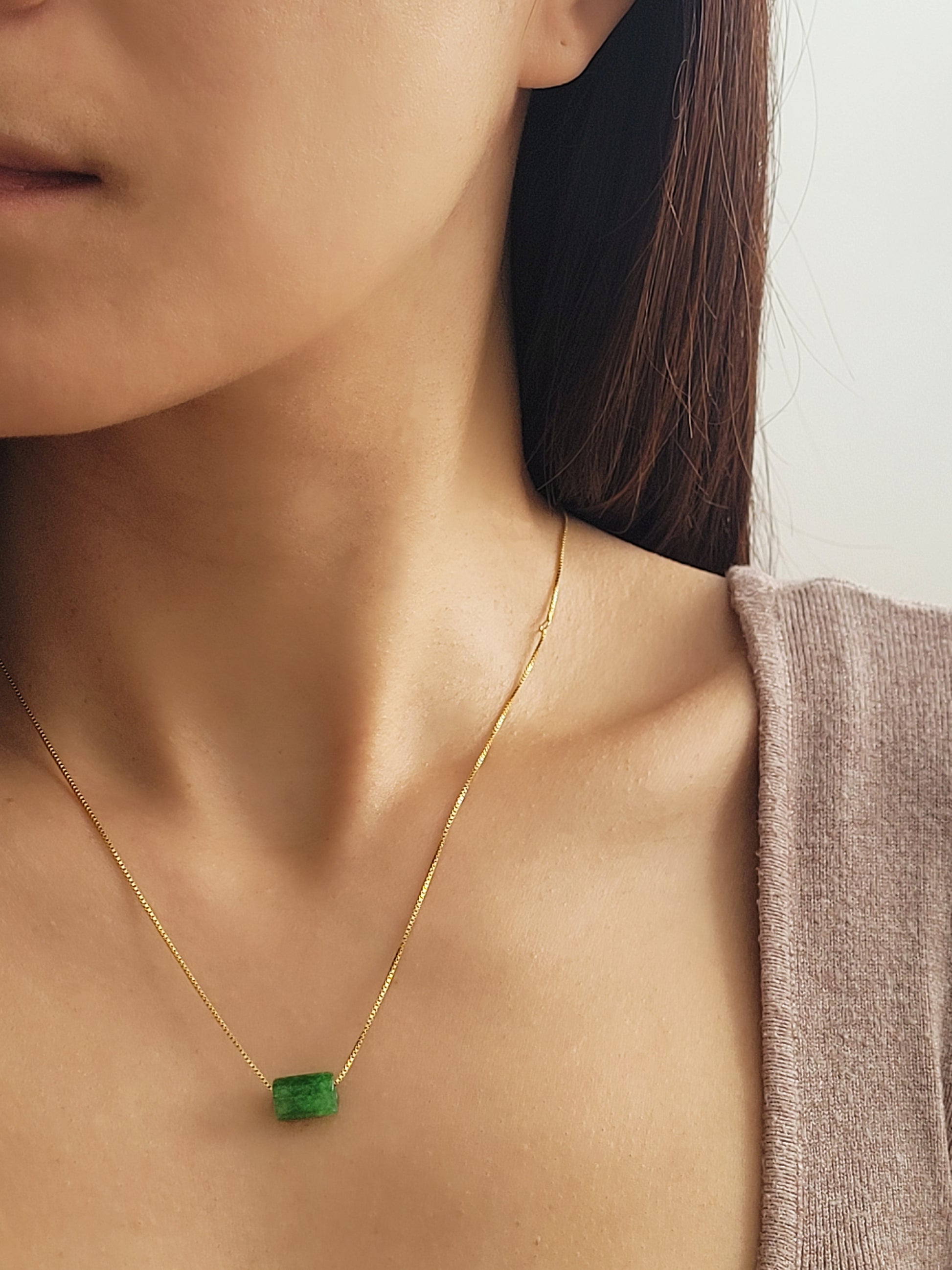 A natural green jade bead necklace with a polished finish, strung on a gold-plated sterling silver chain, offering a minimalist and elegant style.