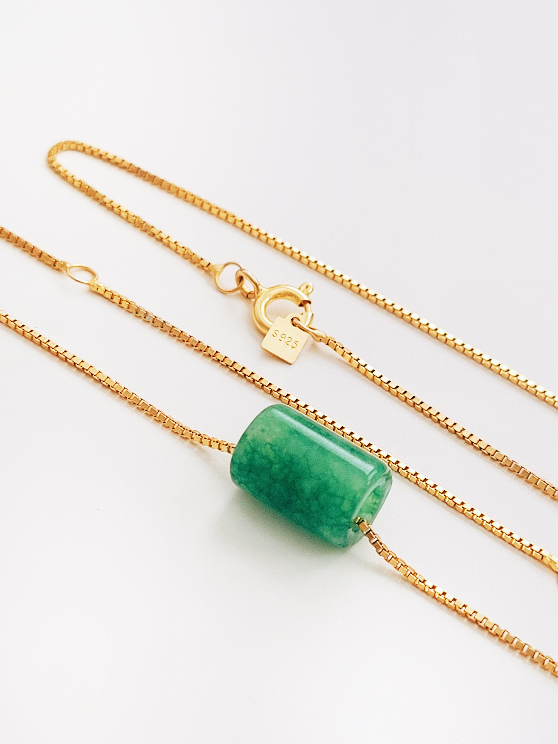 A natural green jade bead necklace with a polished finish, strung on a gold-plated sterling silver chain, offering a minimalist and elegant style.