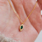 Close-up of a marquise emerald green evil eye pendant necklace on a delicate gold chain, showcasing its dainty and elegant vintage-inspired design.