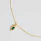 Close-up of a marquise emerald green evil eye pendant necklace on a delicate gold chain, showcasing its dainty and elegant vintage-inspired design.