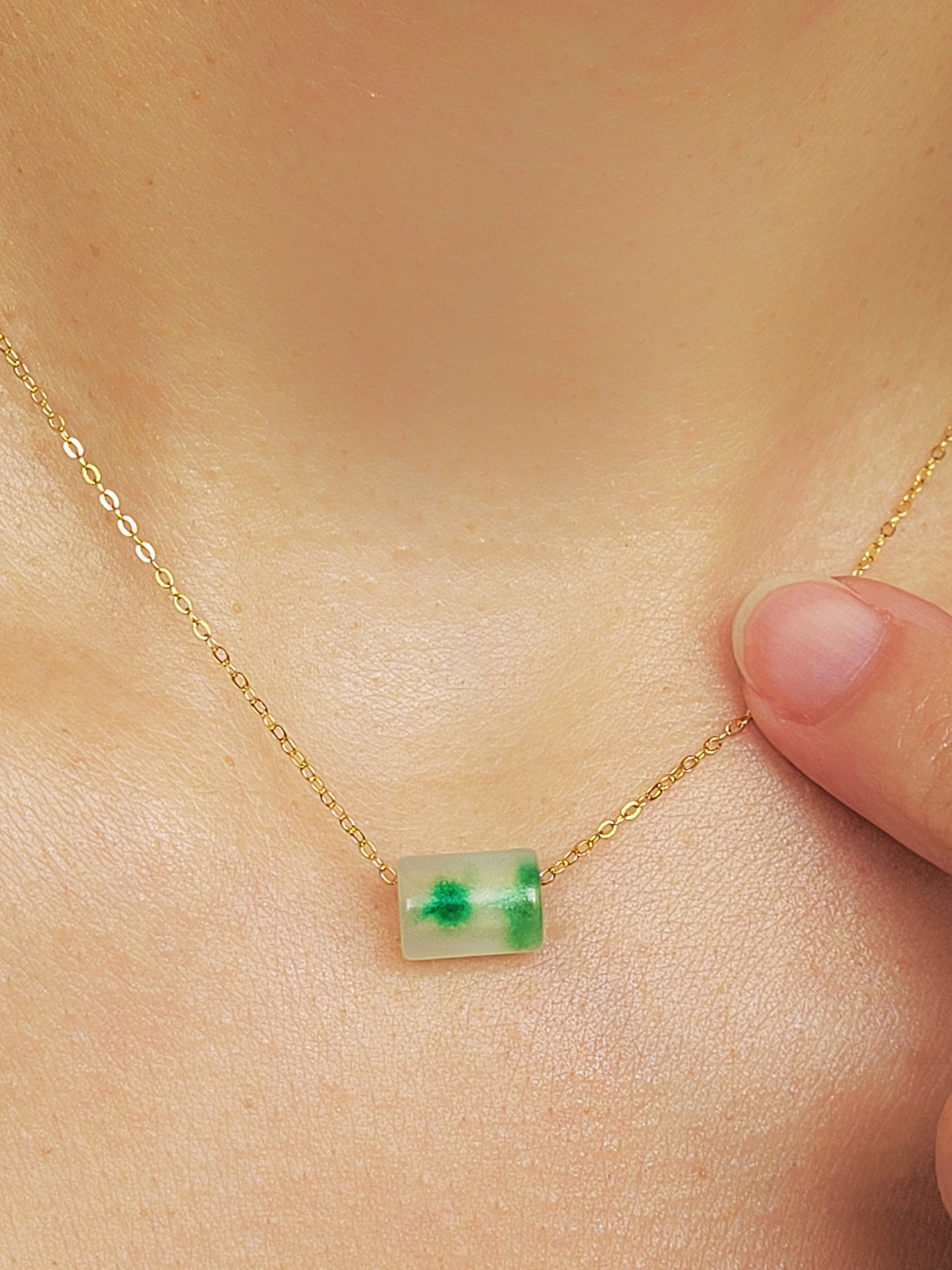 A close-up of a pair of natural jade charm necklace, featuring an icy green jade or icy blue jade pendant on a gold-plated sterling silver chain, showcasing a delicate and elegant look.