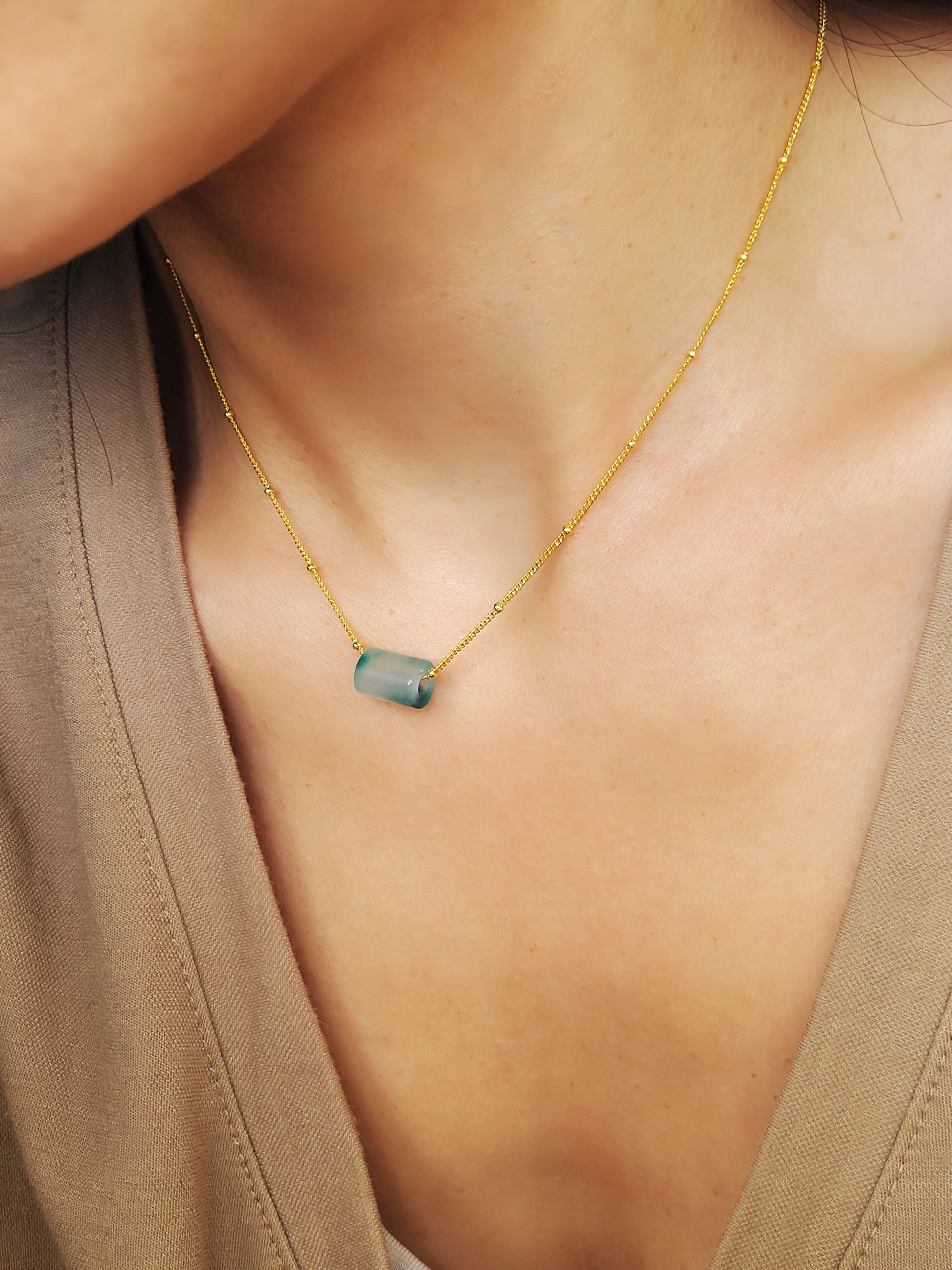 A close-up of a pair of natural jade charm necklace, featuring an icy green jade or icy blue jade pendant on a gold-plated sterling silver chain, showcasing a delicate and elegant look.