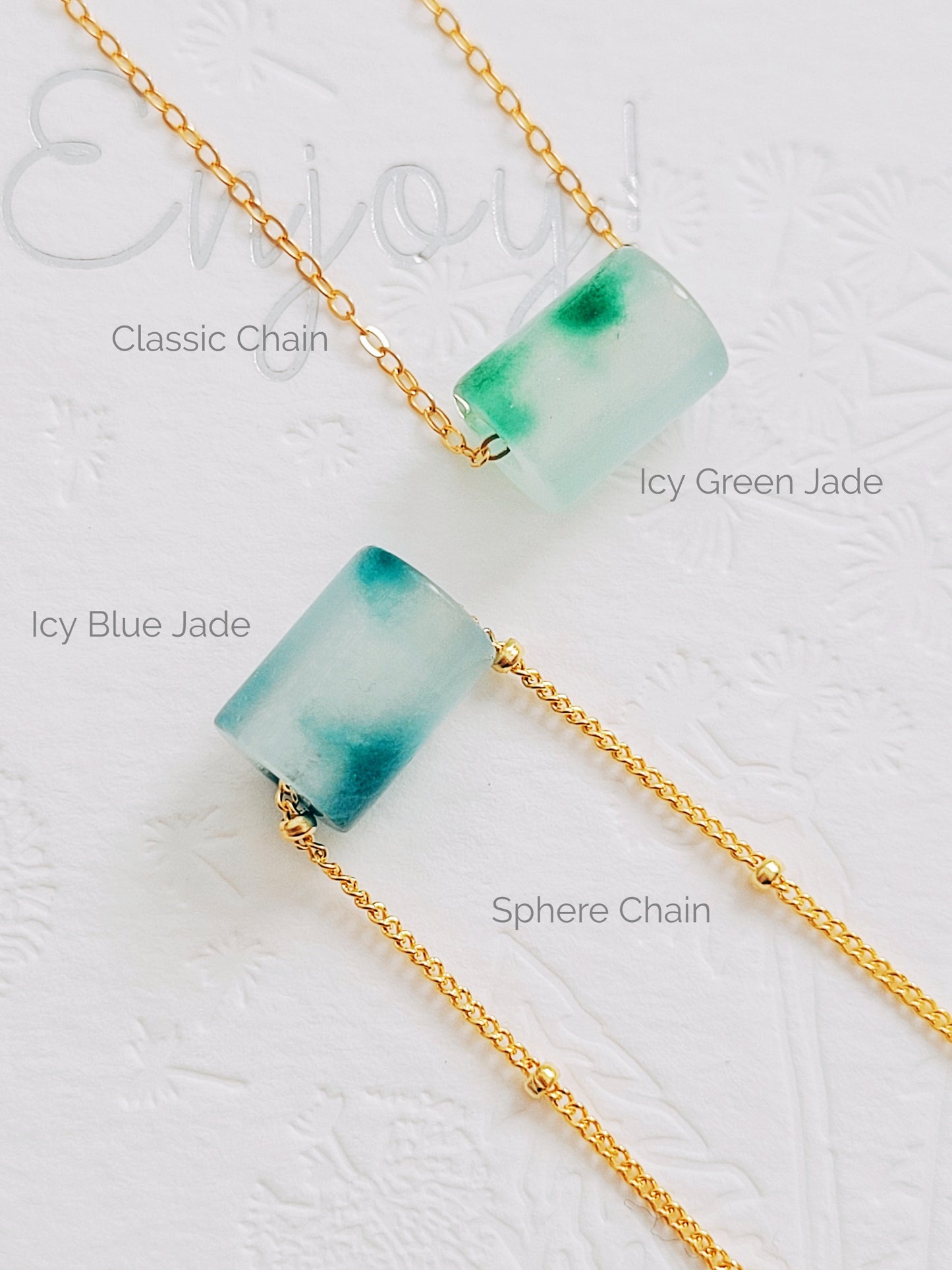 A close-up of a pair of natural jade charm necklace, featuring an icy green jade or icy blue jade pendant on a gold-plated sterling silver chain, showcasing a delicate and elegant look.