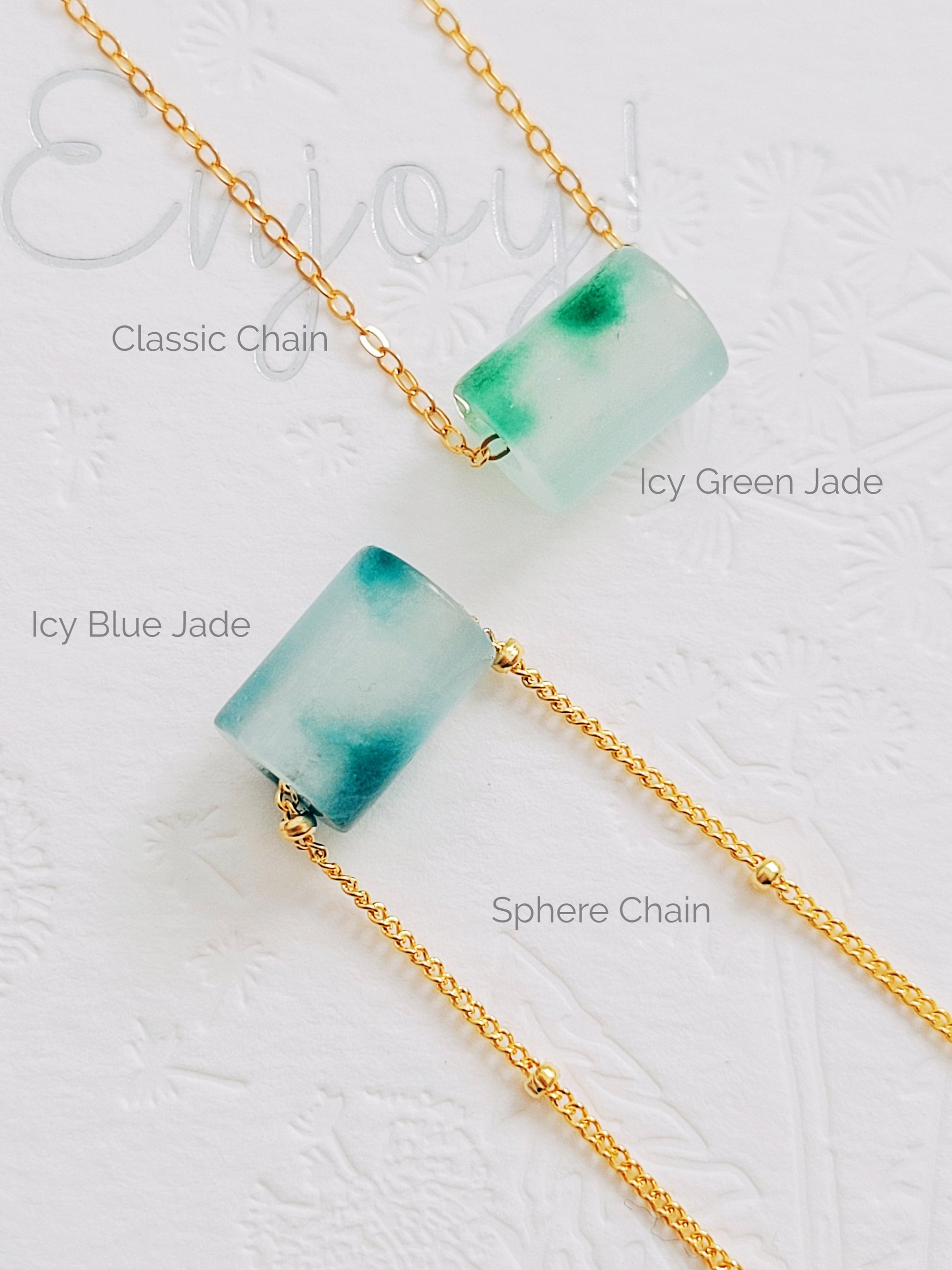 A close-up of a pair of natural jade charm necklace, featuring an icy green jade or icy blue jade pendant on a gold-plated sterling silver chain, showcasing a delicate and elegant look.