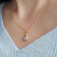 A woman wearing a dainty vintage inspired topaz and gold necklace with a green cubic zirconia.  Perfect anniversary gift for her.