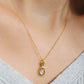 A woman wearing a dainty vintage inspired topaz and gold necklace with a green cubic zirconia.  Perfect anniversary gift for her.