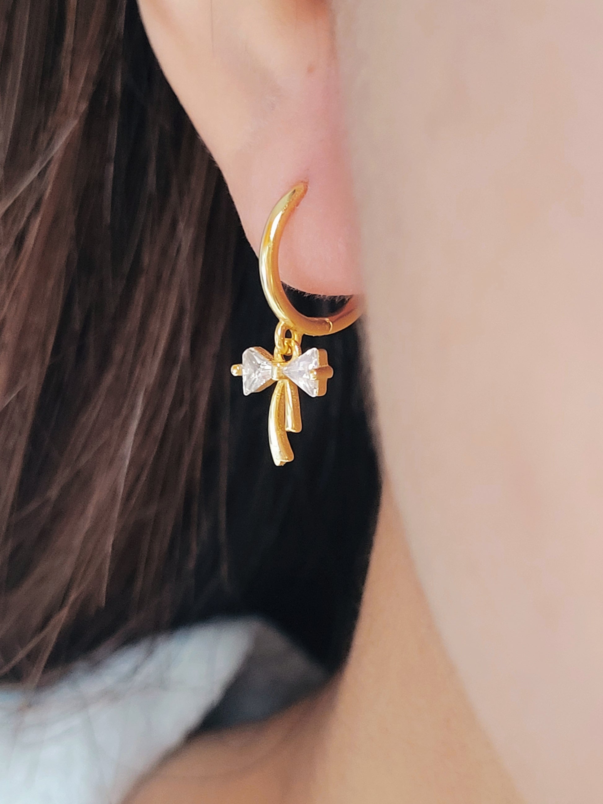 Close-up view of a woman's ear wearing ribbon bow earring with a dangling design, perfect for gifting to girlfriends, daughters, or loved ones.