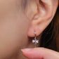 Close-up view of a woman's ear wearing silver ribbon bow earring with a dangling design, perfect for gifting to girlfriends, daughters, or loved ones.