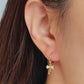 Close-up view of a woman's ear wearing gold ribbon bow earring with a dangling design, perfect for gifting to girlfriends, daughters, or loved ones.