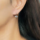 Close-up view of a woman's ear wearing silver ribbon bow earring with a dangling design, perfect for gifting to girlfriends, daughters, or loved ones.