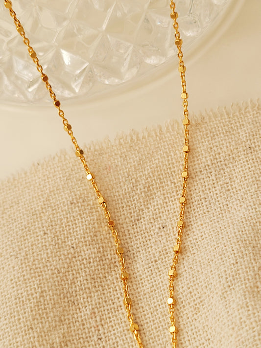Close-up of a dainty gold necklace with square station beads, reflecting light with subtle shimmer, ideal for daily wear. Crafted in gold plated sterling silver, perfect jewellery for everyday wear. A thoughtful gift for birthdays, anniversaries or any occasions.