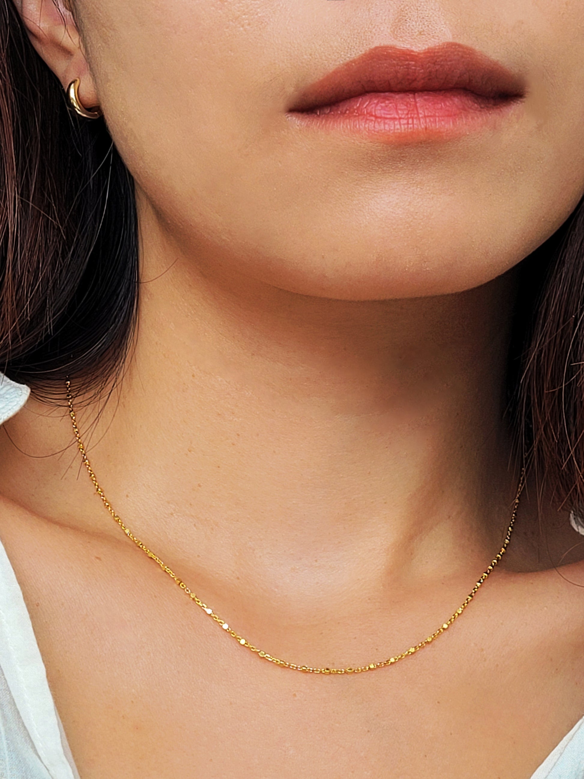Close-up of a dainty gold necklace with square station beads, reflecting light with subtle shimmer, ideal for daily wear. Crafted in gold plated sterling silver, perfect jewellery for everyday wear. A thoughtful gift for birthdays, anniversaries or any occasions.