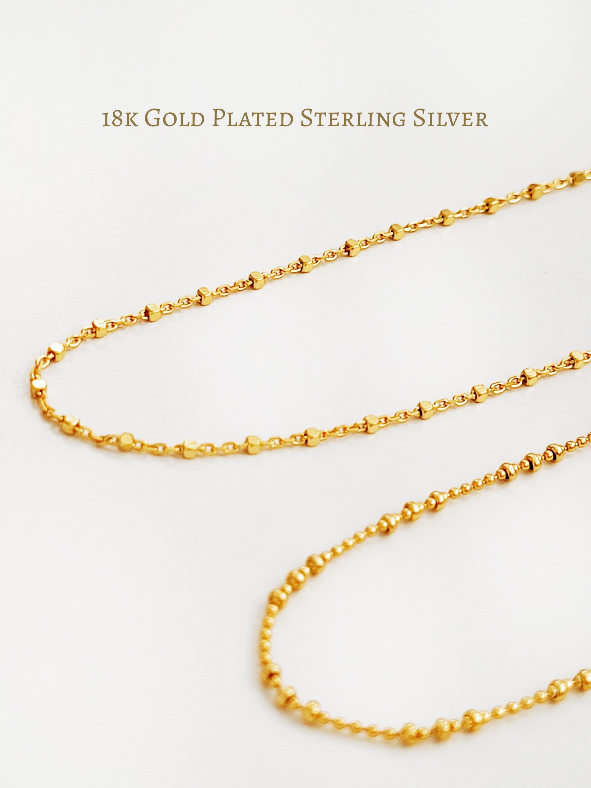 A gold-plated sterling silver necklace with a series of square beads linked together, displayed against a white background.