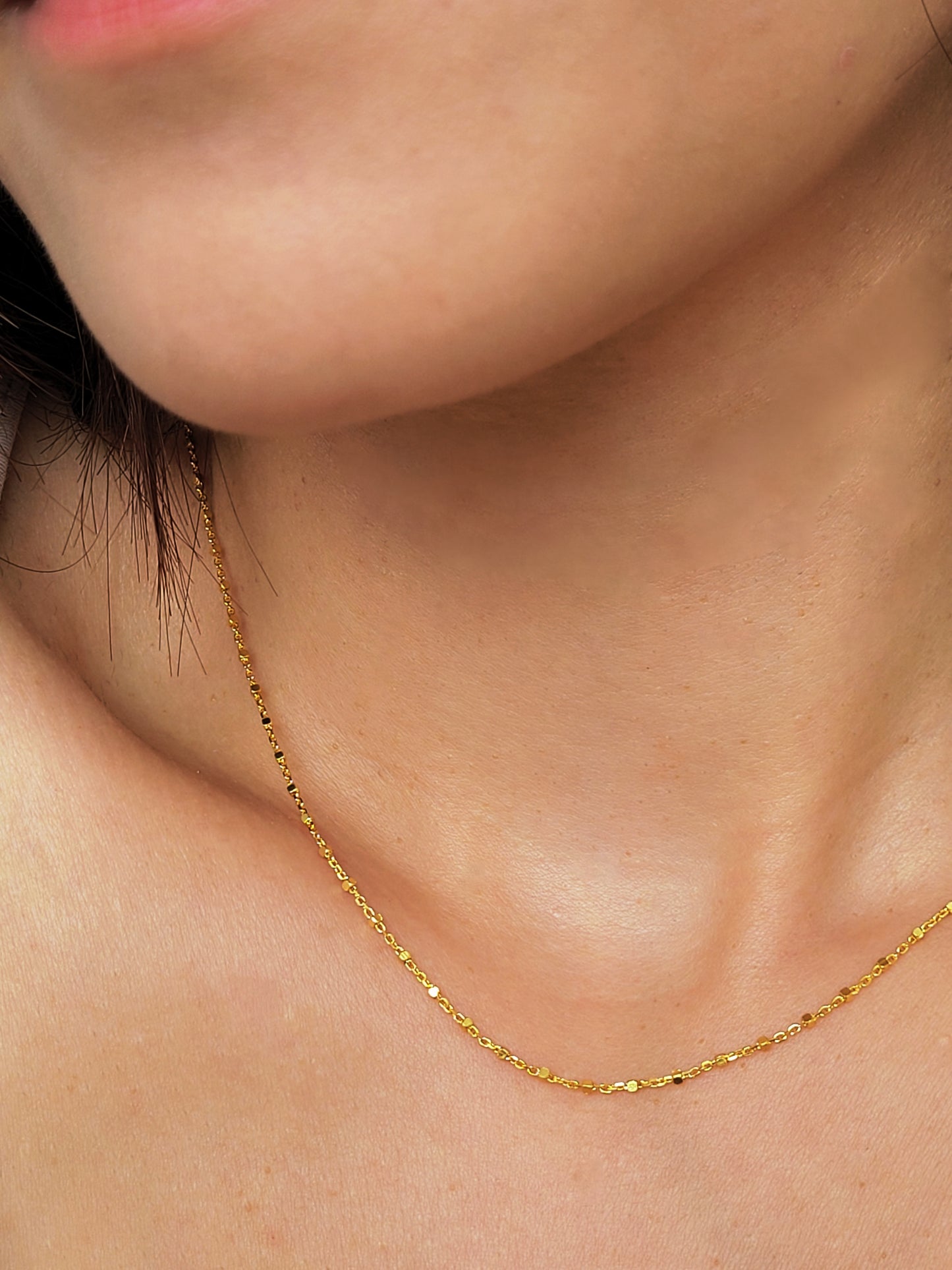 Close up of a woman wearing a minimalist gold chain necklace