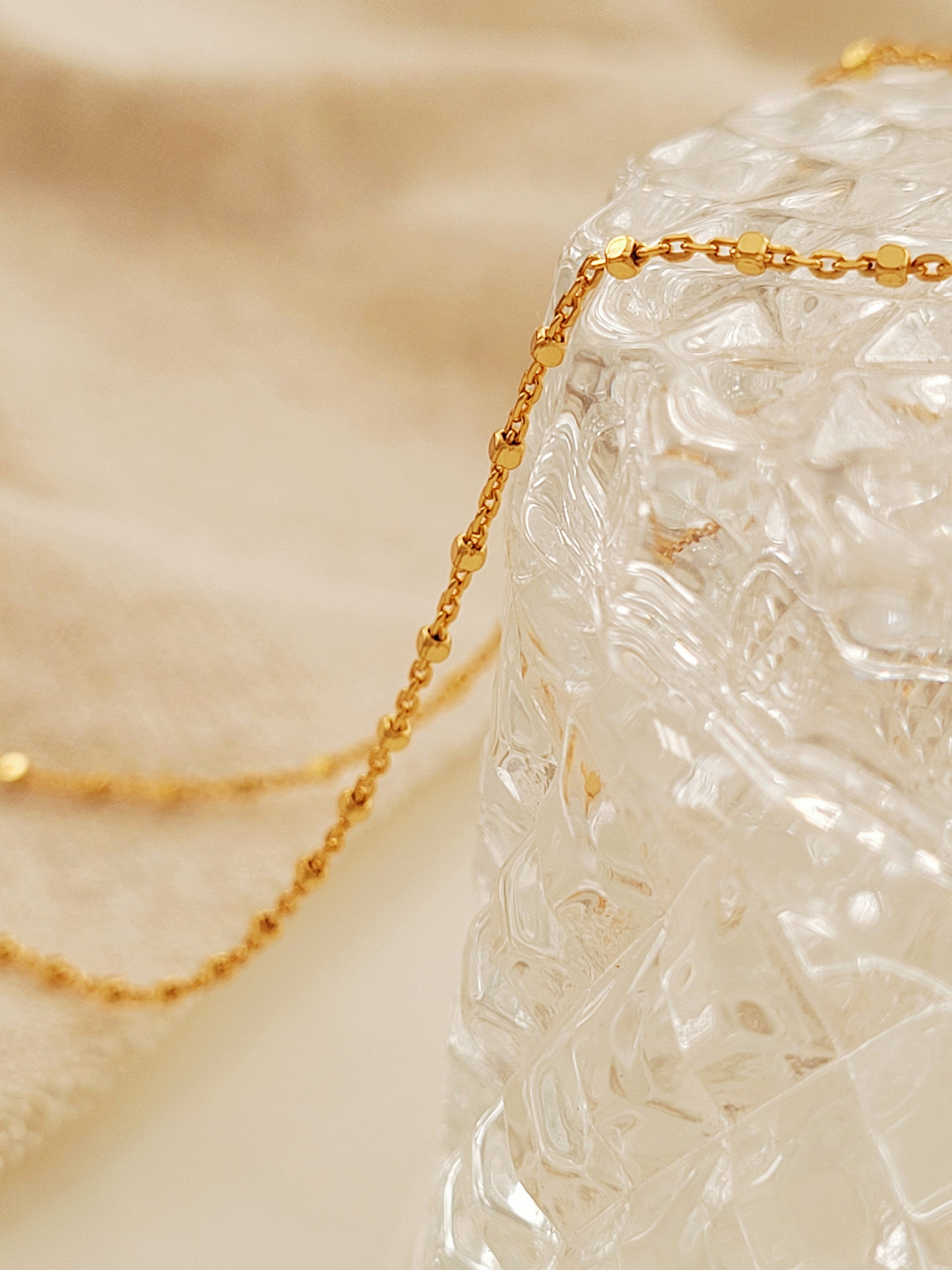 Close up of a gold chain necklace on a glassware