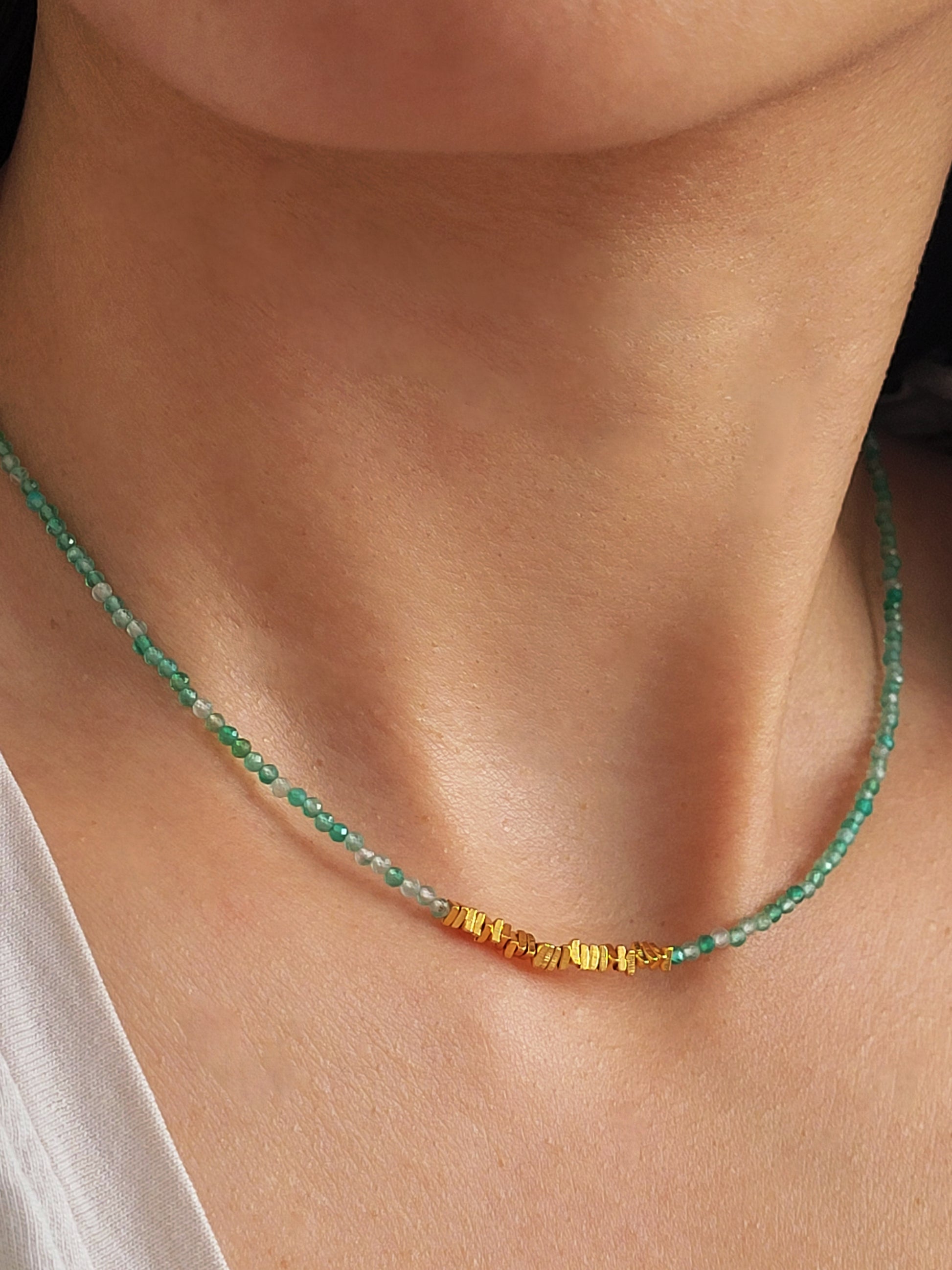 A woman wearing green onyx beaded gemstone choker necklace with gold vermeil accents, showing casing its fine jewellery details and elegance.