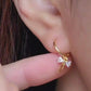 Close-up view of a woman's ear wearing gold ribbon bow earring with a dangling design, perfect for gifting to girlfriends, daughters, or loved ones.