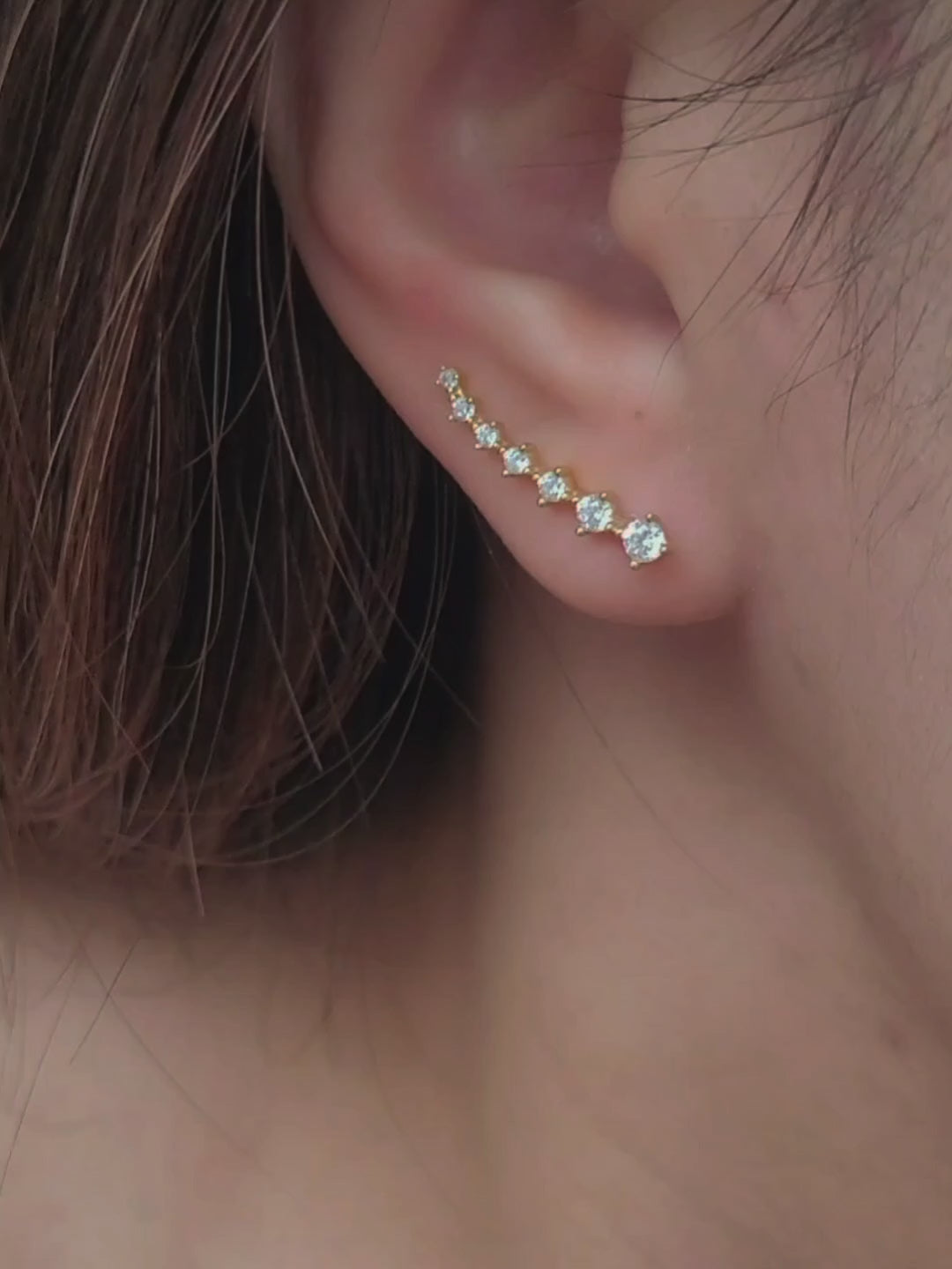 Close-up of a woman's ear wearing an 18K gold-plated cubic zirconia climber earring, highlighting the elegant and minimalist design.