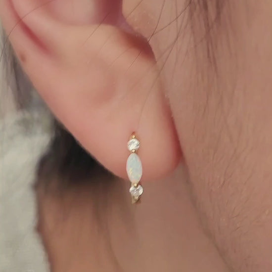 Close up of 18k gold plated sterling silver marquise opal huggie earrings, featuring a luminous opal accented with sparkling cubic zirconia.