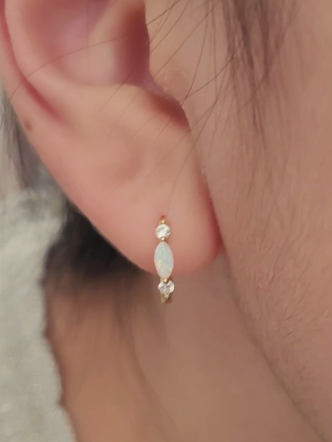 Close up of 18k gold plated sterling silver marquise opal huggie earrings, featuring a luminous opal accented with sparkling cubic zirconia.