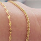 Woman wearing a delicate, gold vermeil skinny chain bracelet on her wrist, adding a subtle shimmer to her cozy. The bracelet's light-reflecting quality highlights its minimalist design, creating an elegant and understated style.