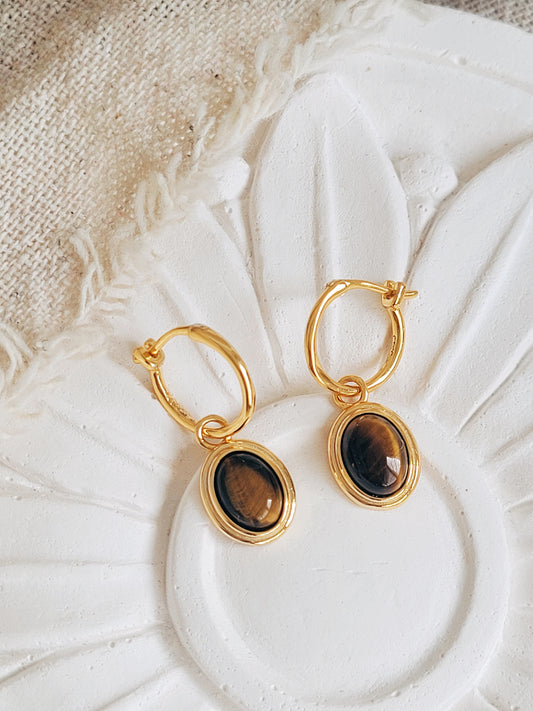Close-up of gold vermeil dangle earrings with tiger's eye gemstone, minimalist and elegant style.